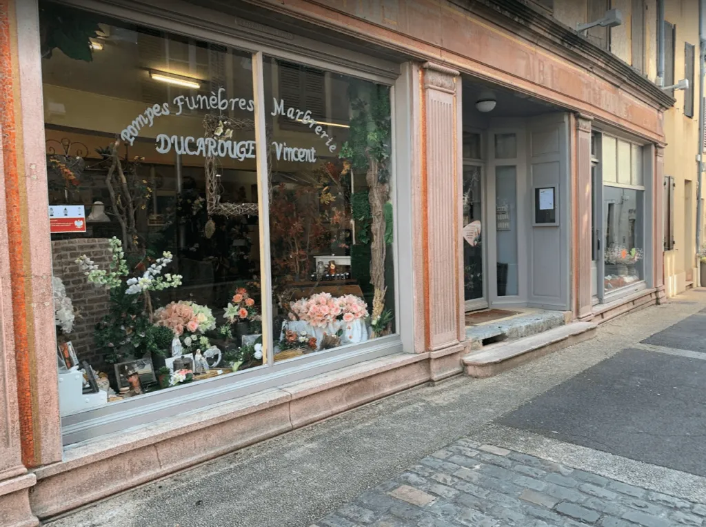 Devanture de l'agence Pompes Funèbres Marbrerie Ducarouge Vincent avec vitrine d'articles funéraires
