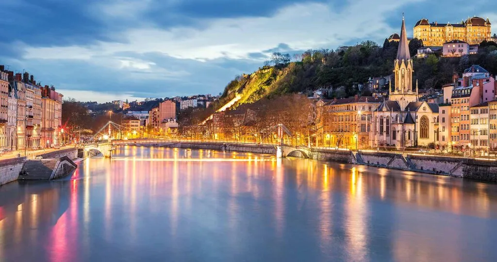 Lyon au crépuscule sur la Saône avec l'église Saint-Georges et Fourvière éclairées